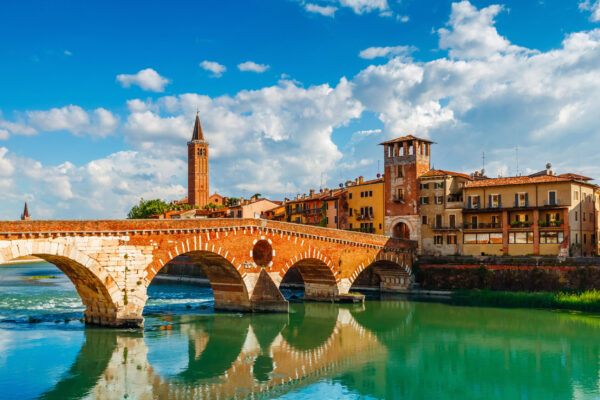 Bridge Ponte Pietra in Verona on Adige river Bridge Ponte Pietra in Verona on Adige river. Veneto region. Italy. Sunny summer day panorama and blue sky with clouds. Ancient european terracotta color houses